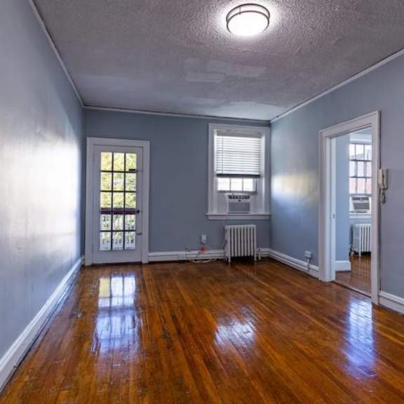 a room with wooden floors and a window with blinds.