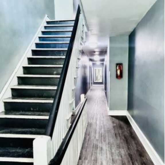 a staircase with a black handrail and wooden steps leading to a door.