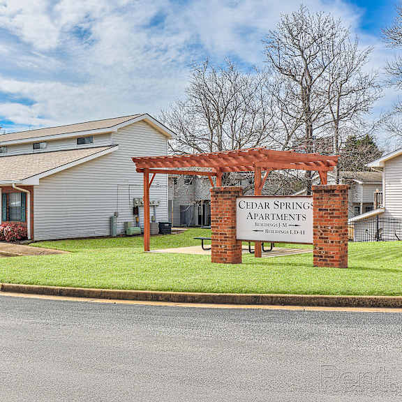 the image shows a building with a sign that reads "cedar springs apartments.".
