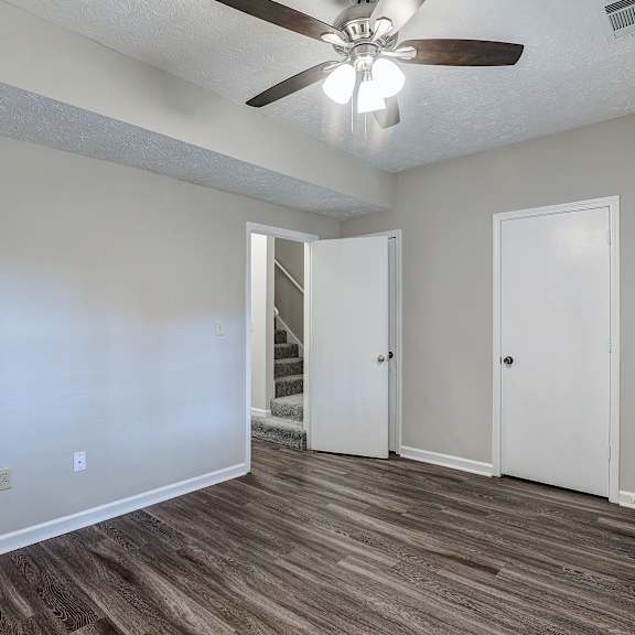 a room with a ceiling fan and wooden flooring.
