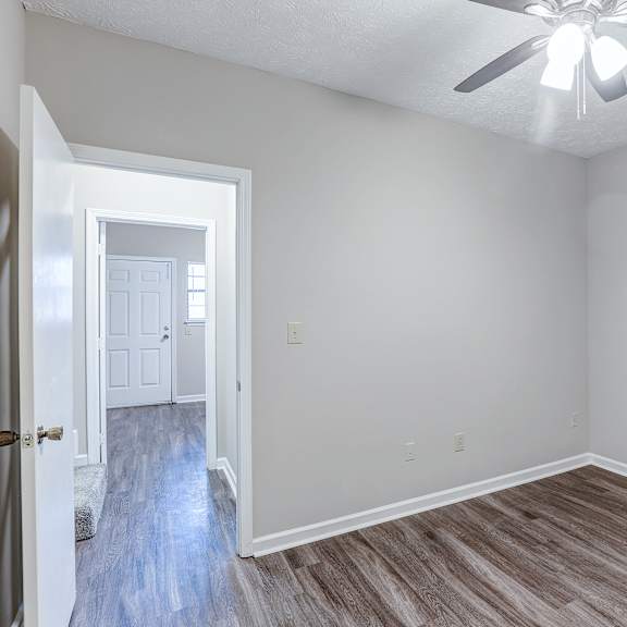 a room with a ceiling fan and light, and a doorway leading to another room.