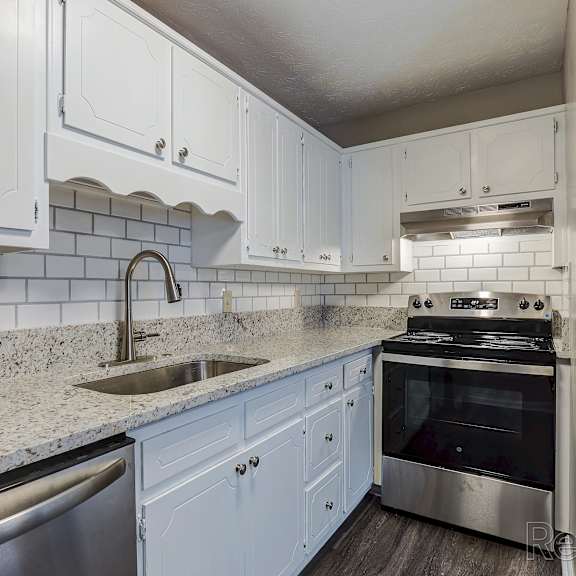 a kitchen with white cabinets and a stainless steel sink and oven.