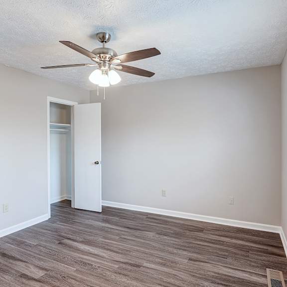 a room with a ceiling fan and wooden flooring.