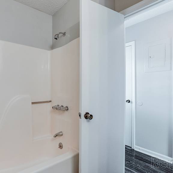 a white bathroom with a tub and a door.