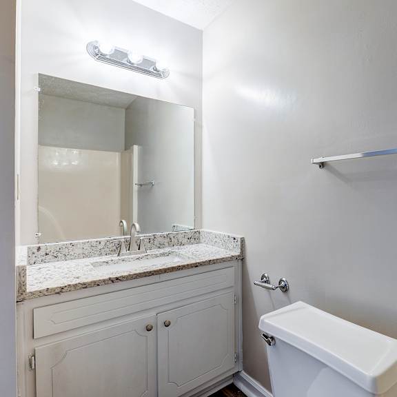 a white bathroom with a toilet, sink, and mirror.