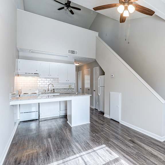 a spacious kitchen with white cabinets and a wooden floor.