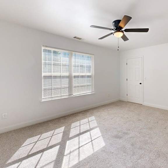 a room with a ceiling fan and a window with blinds.