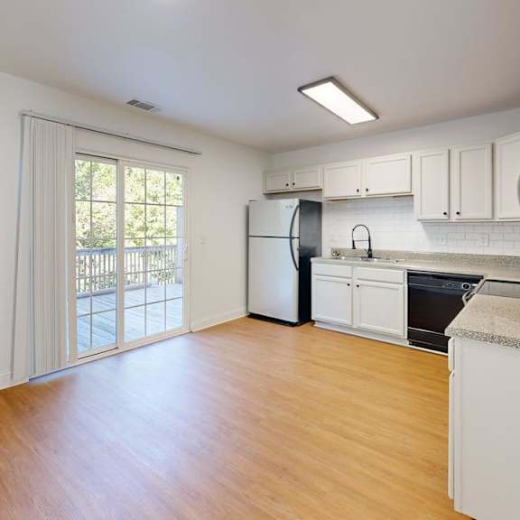 a kitchen with white cabinets and a wooden floor.
