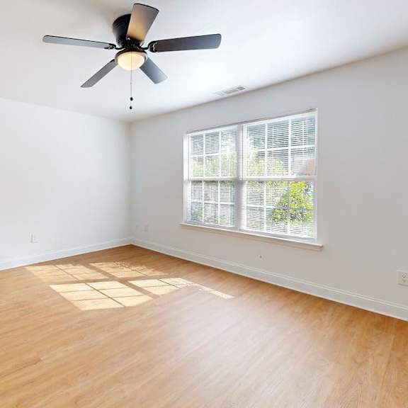 a room with a ceiling fan and a window letting in sunlight.