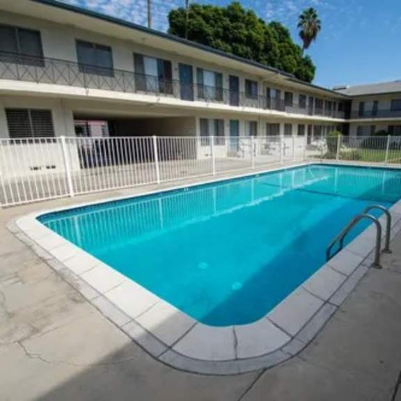 a swimming pool in a courtyard surrounded by a white fence.