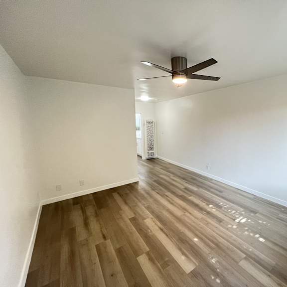 a room with a ceiling fan and wooden flooring.