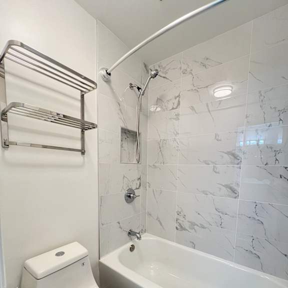 a white toilet sits next to a bathtub in a bathroom.