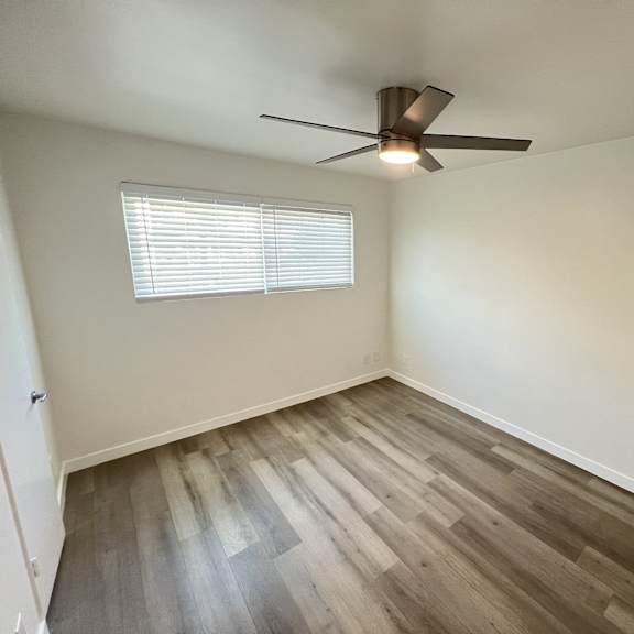 a room with a ceiling fan and a window with blinds.