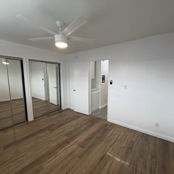 a room with a ceiling fan and wooden flooring.