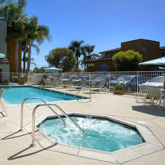 a pool with a hot tub and chairs around it.