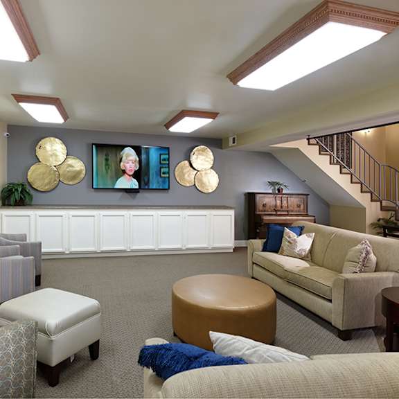 a living room with a striped chair, a couch, and a blue ottoman.