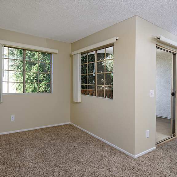 a room with a carpeted floor and two windows.
