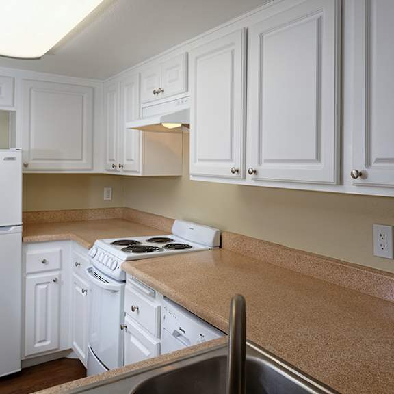 a kitchen with white cabinets and a white fridge.