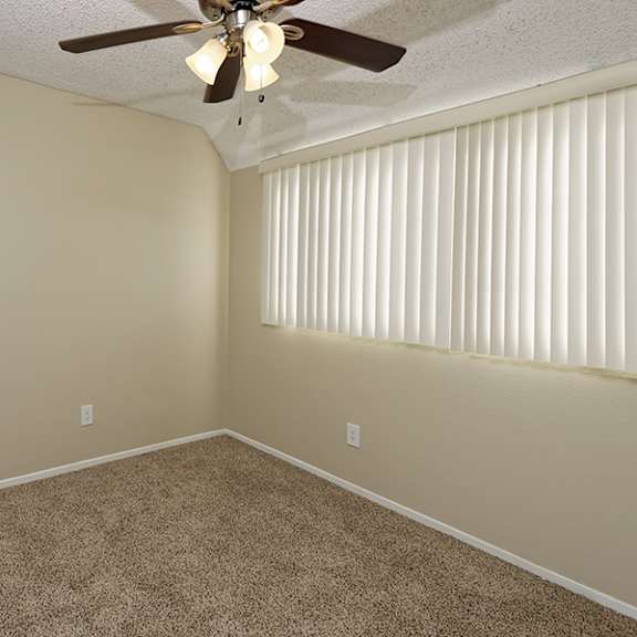 a room with a ceiling fan and a window with blinds.