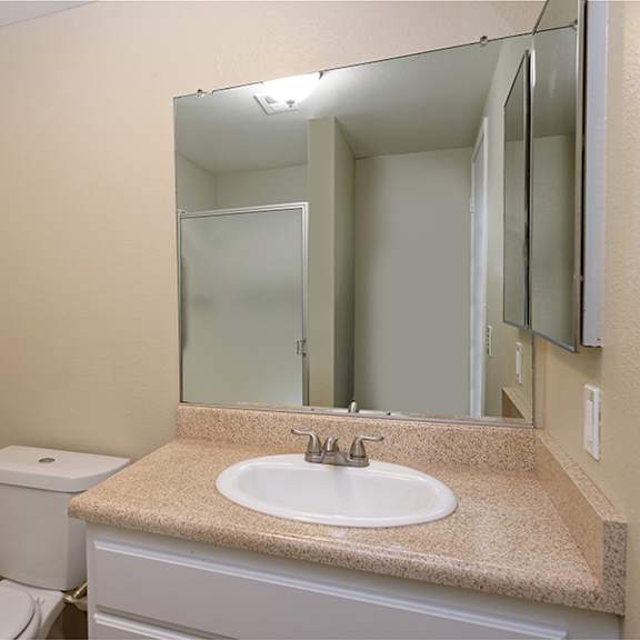 a bathroom with a sink, toilet and mirror.
