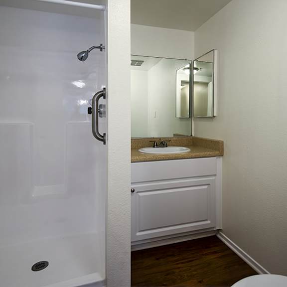 a white bathroom with a toilet, sink, and shower.