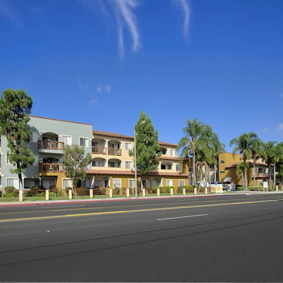 a row of apartment buildings with trees in front of them.