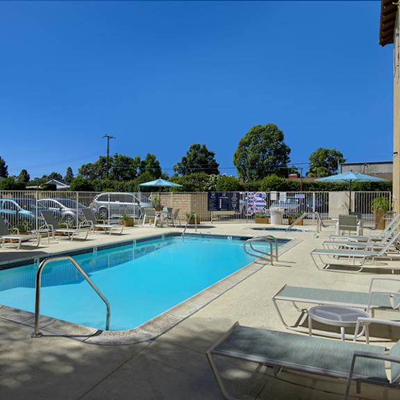 a large swimming pool surrounded by sun loungers and umbrellas.