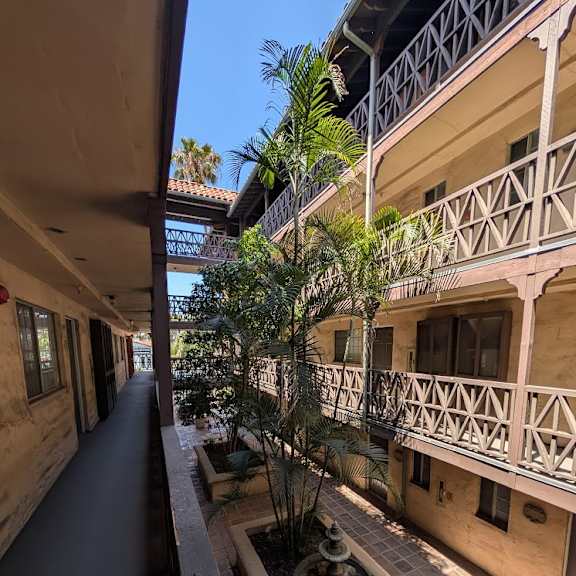 a balcony with a railing and a tree in a planter box.