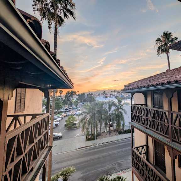 a view from a balcony overlooking a parking lot and palm trees.