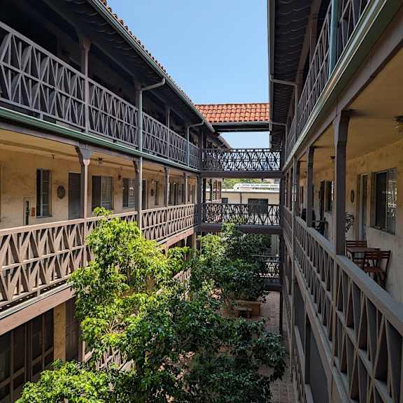 a balcony with a green railing overlooks a courtyard.