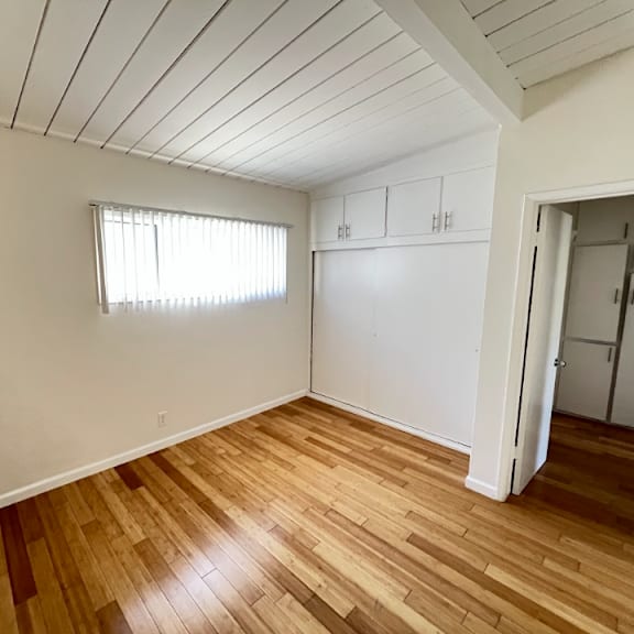 a room with wooden floors and a window with blinds.