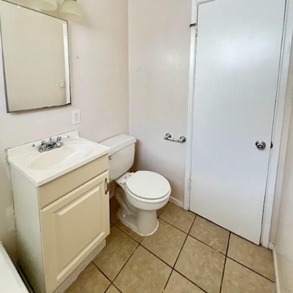 a white bathroom with a toilet, sink, and mirror.
