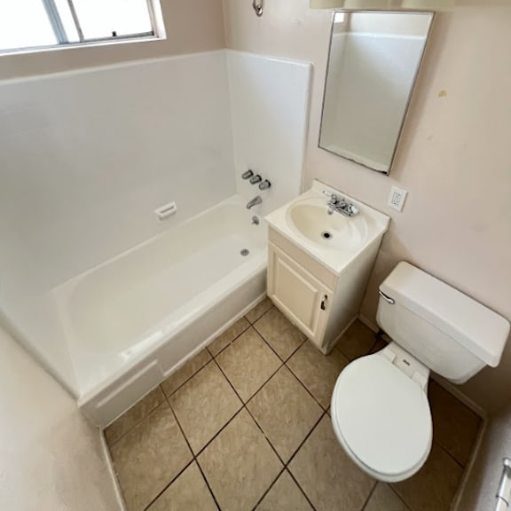 a small bathroom with a toilet, sink, and bathtub.