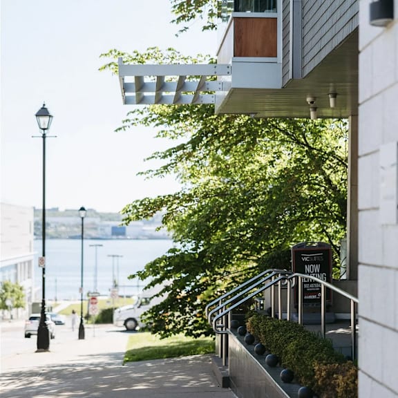 a white building with a black lamp post on the left and a tree in front of it.