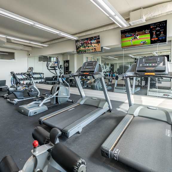 a gym with treadmills, exercise bikes, and other equipment.