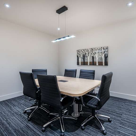 a conference room with a table, chairs, and a painting on the wall.