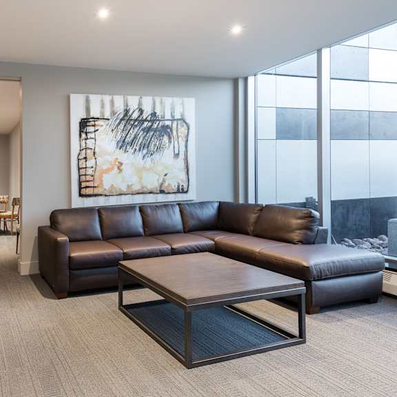a living room with a brown leather couch and a painting on the wall.