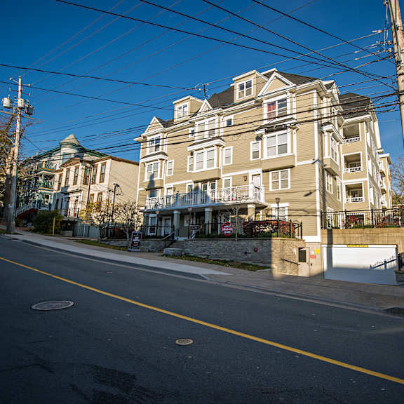 a street view of a residential area with apartment buildings and a clear blue sky.