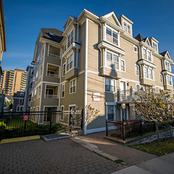 a large, multi-story apartment building with a black fence and gate in front.