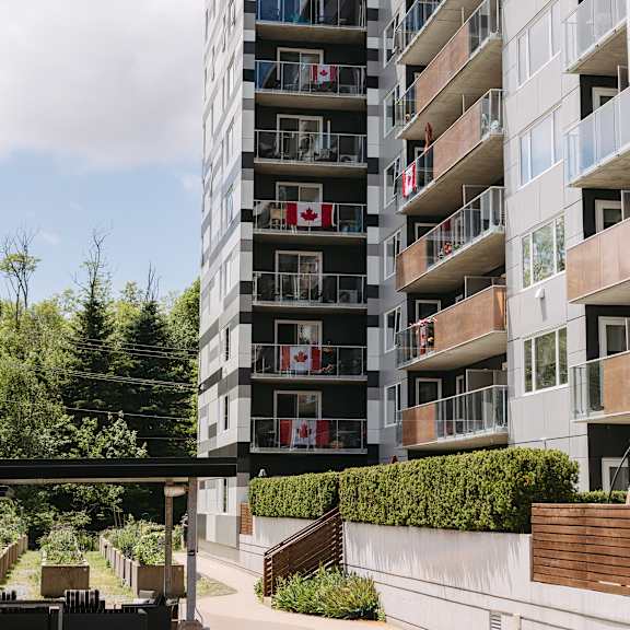 a tall residential building with balconies and flags on the windows.