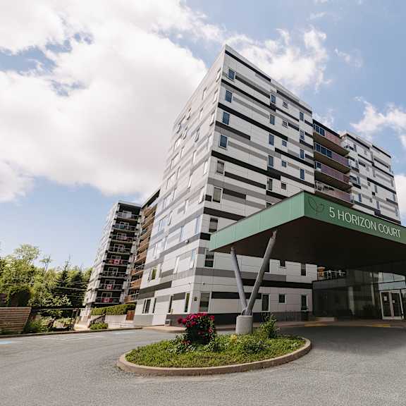 the image shows a modern building with a glass entrance and a green awning.