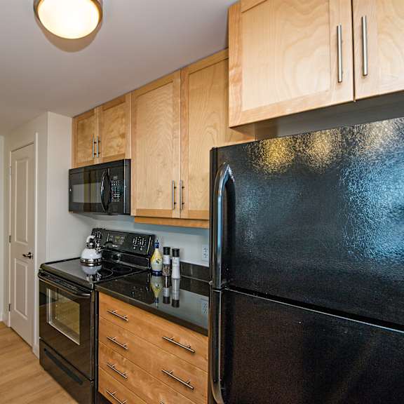 a black refrigerator is in a kitchen with wooden cabinets.
