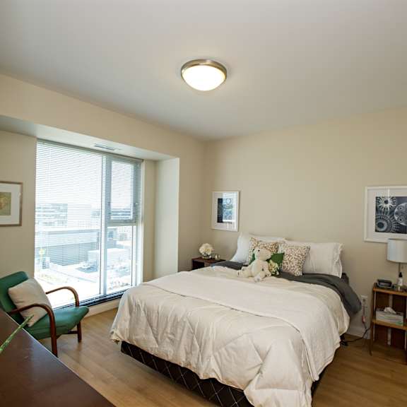 a bedroom with a bed, chair, and window.