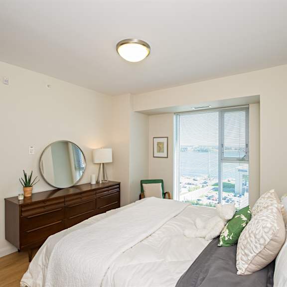 a bedroom with a large bed and a mirror on the dresser.