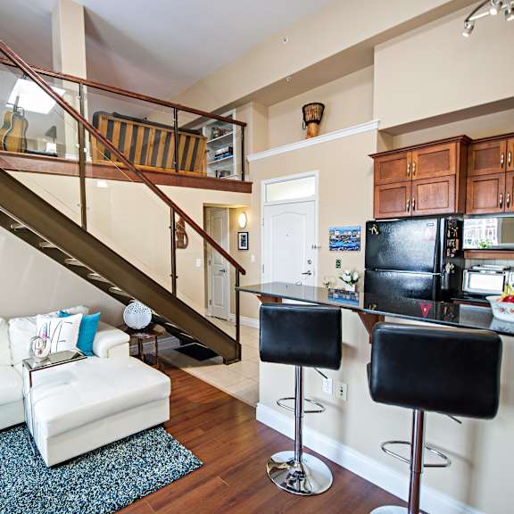 a living room with a staircase and a kitchen area.