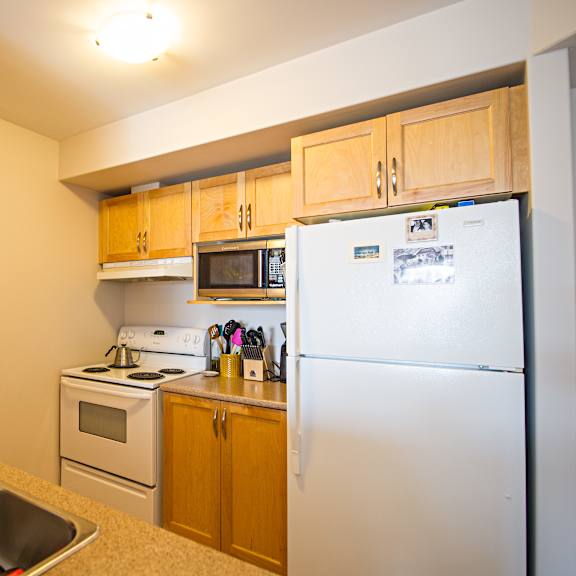 a kitchen with a refrigerator, sink, and stove.