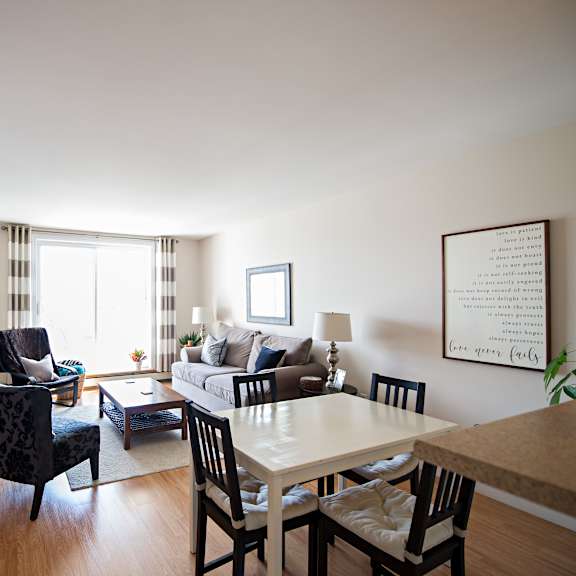 a well-lit living room with a dining table and chairs.