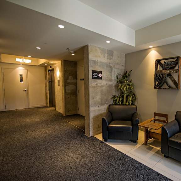 two black leather couches in a room with a stone wall.