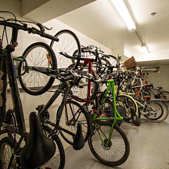 a bike rack full of bicycles in a white hallway.