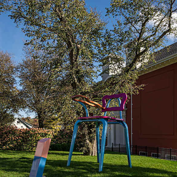 a blue and pink chair sits on a grassy area next to a small blue object.